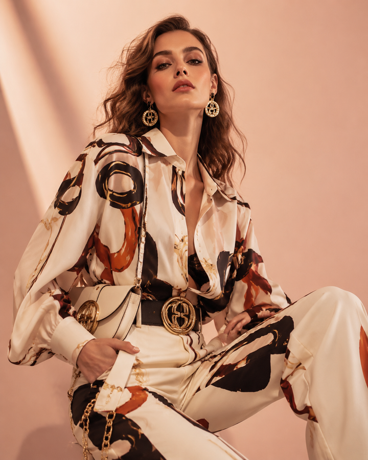 Editorial of a confident woman in a bold logo-forward outfit with gold hardware, rose-gold and cream studio, cinematic light, no text, no watermark